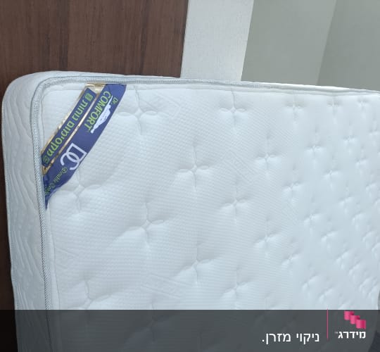 מזרן לבן עומד ליד קיר חום